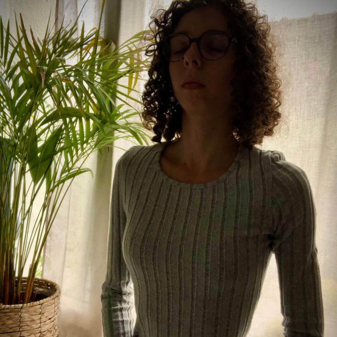 Femme en posture de relaxation, assise sur un tapis au sol, yeux fermés, dans une ambiance apaisante. Atelier bien-être et respiration pour futures mamans, jeunes mamans et femmes dans le Nord (Arras, Douai, Valenciennes, Orchies, Cambrai, Somain, Lens, Hénin-Beaumont...)