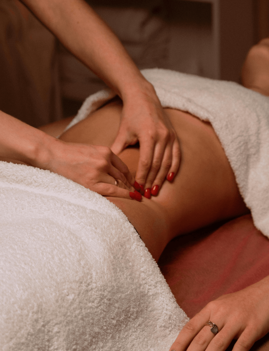 Femme en post-partum recevant un massage relaxant à son domicile dans une ambiance douce et apaisante.