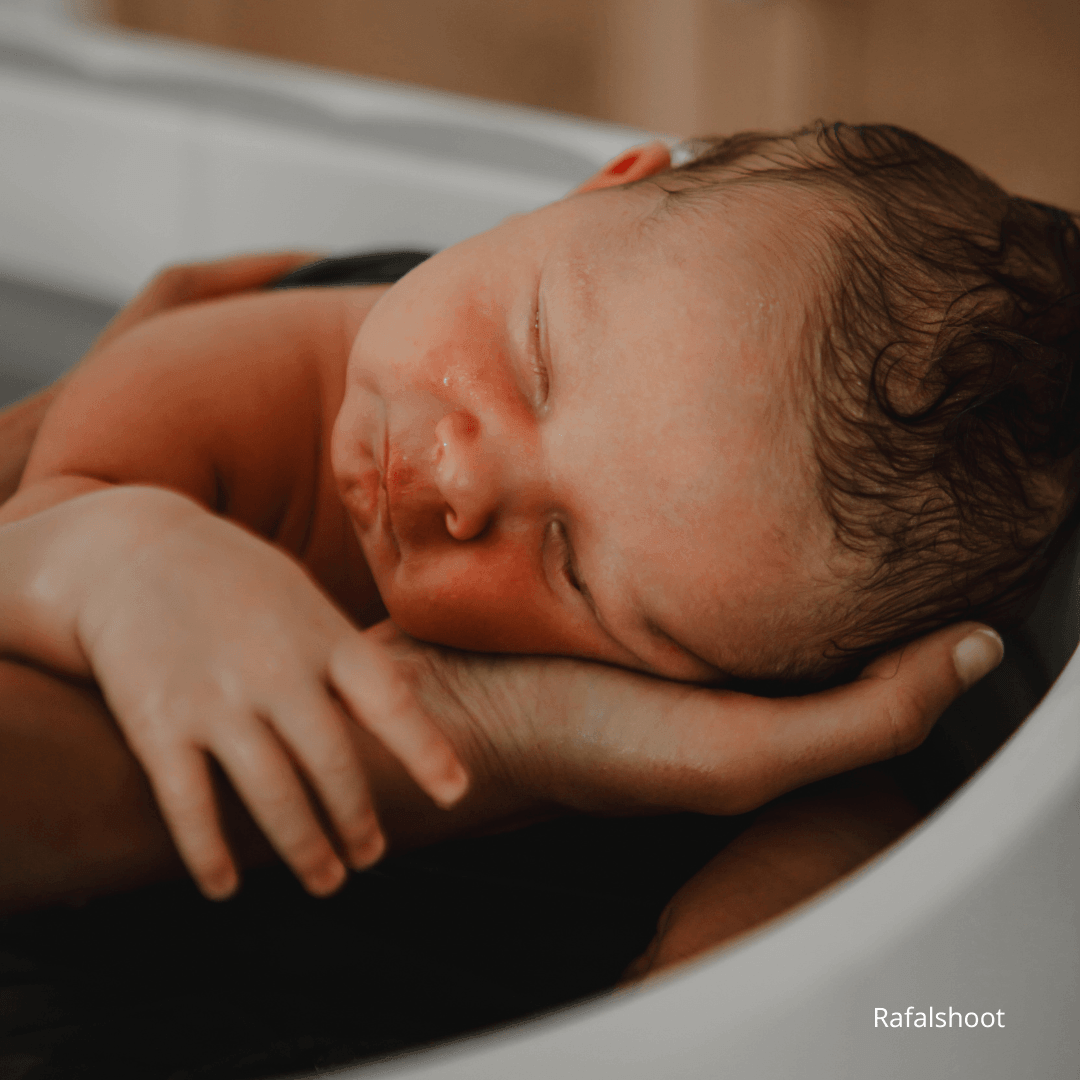 Bain enveloppé pour nouveau-né dans un lange, bébé immergé dans l’eau pour un moment de détente, de sécurité et de bien-être périnatal.