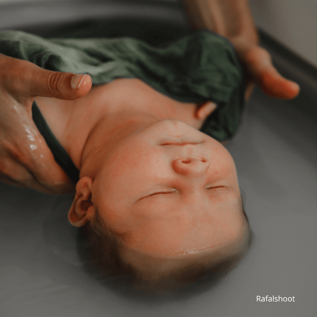 Bain enveloppé pour nouveau-né dans un lange, bébé immergé dans l’eau pour un moment de détente, de sécurité et de bien-être périnatal.